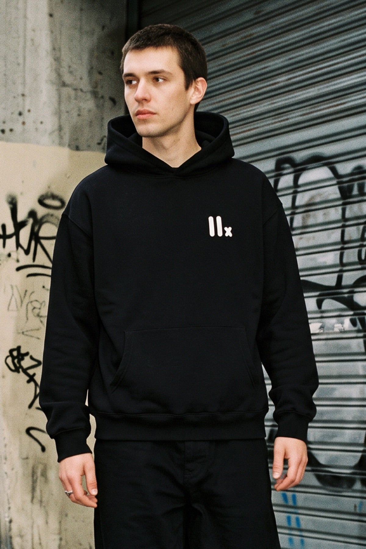 IIX black hoodie in front of a graffiti shutter